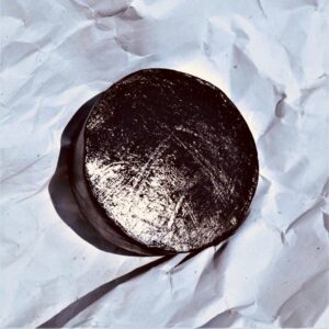 a shiny round black soap, handmade with activated charcoal