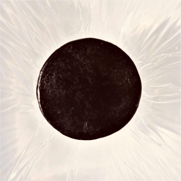 black_soap3 a round black soap, handmade with activated charcoal, laying above water